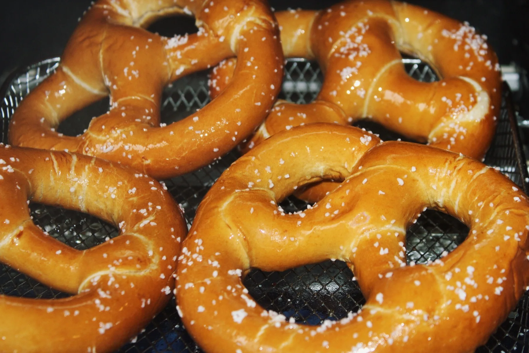 Three golden soft pretzels with dipping sauce
