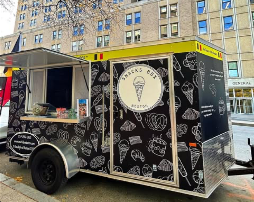 The Snacks Box Boston trailer parked on a street in downtown Boston